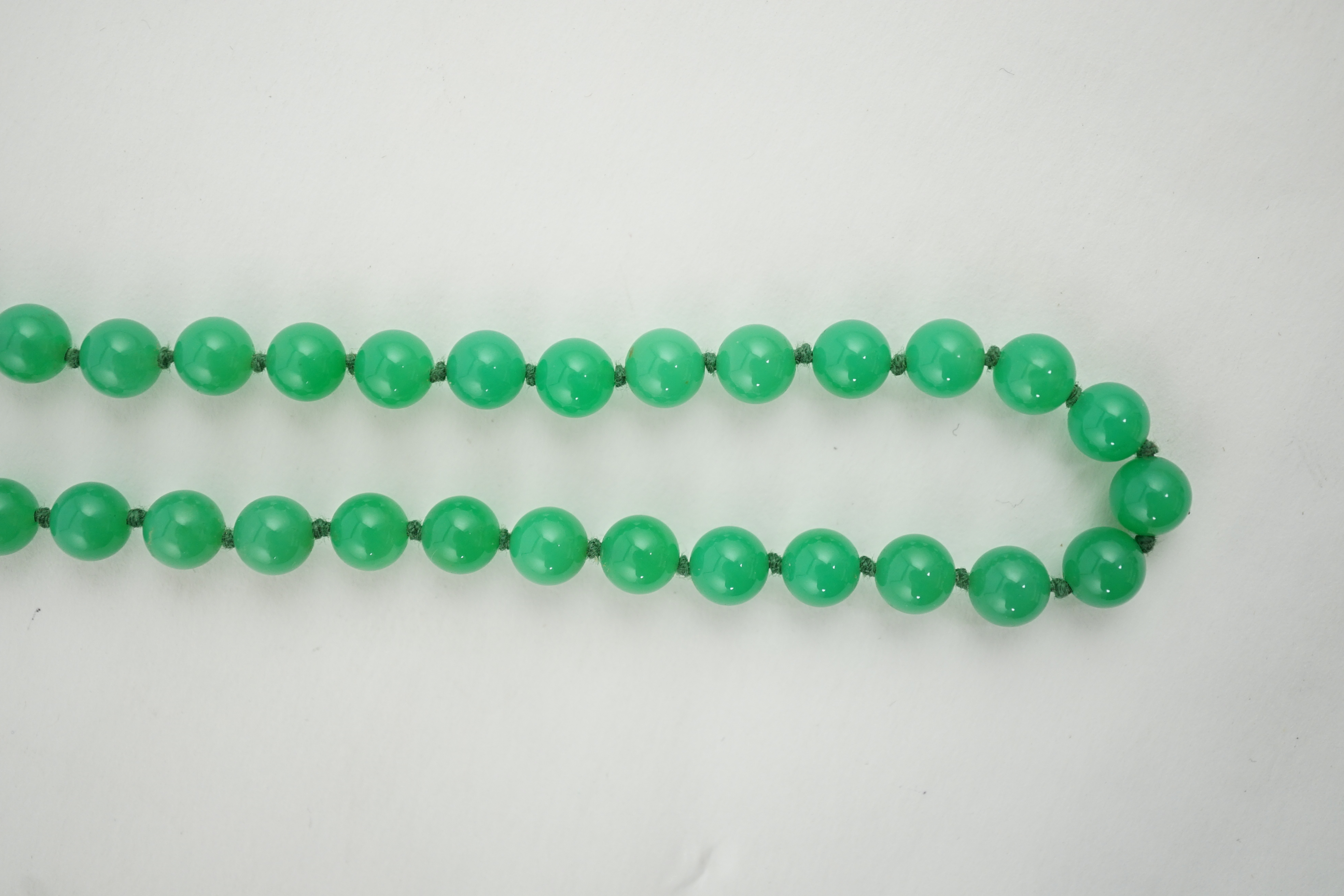 A modern long single strand jadeite bead necklace, with a cabochon jade and diamond chip cluster set 18k clasp